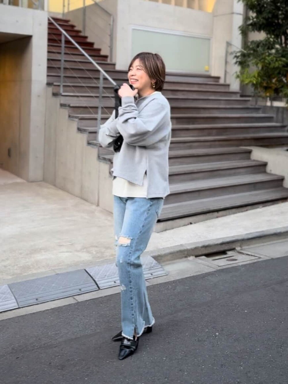 グレー系のスウェット、ブラック系のローファー、ブラック系のトートバッグを着用したレディースの冬コーディネートの2枚目の写真