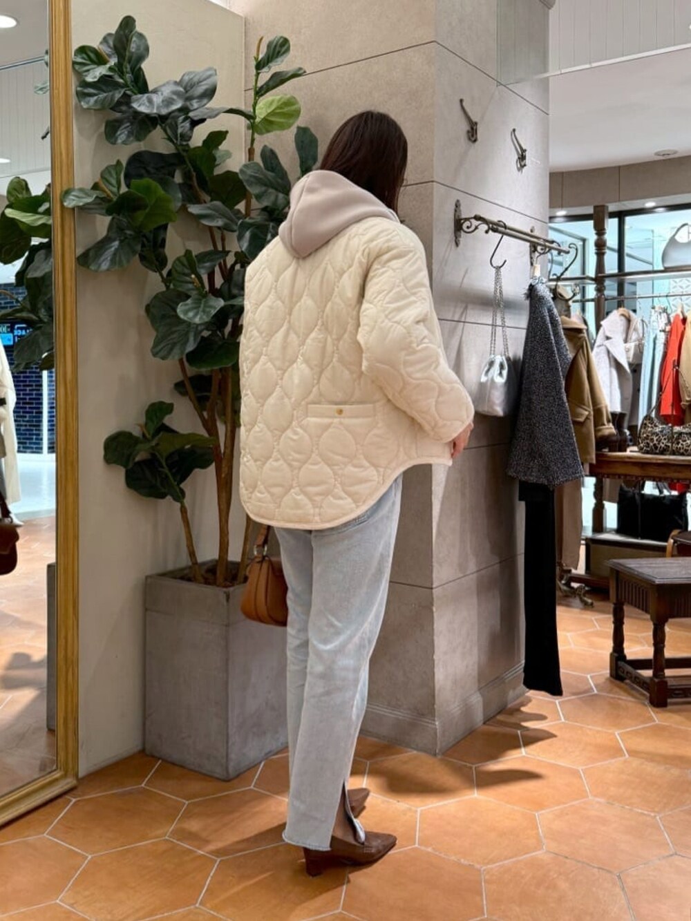 グレー系のニット/セーター、ホワイト系のダウンジャケット/コート、ブルー系のデニムパンツを着用したレディースの秋コーディネートの3枚目の写真