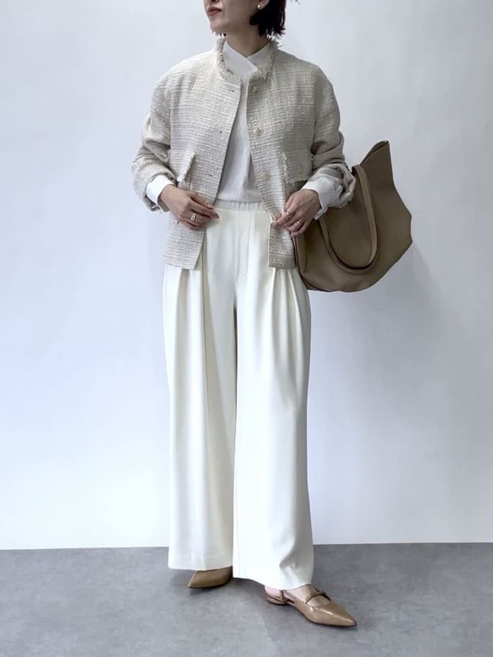 ホワイト系のスラックス、ベージュ系のノーカラージャケット、ベージュ系のトートバッグを着用したレディースの冬コーディネートの4枚目の写真