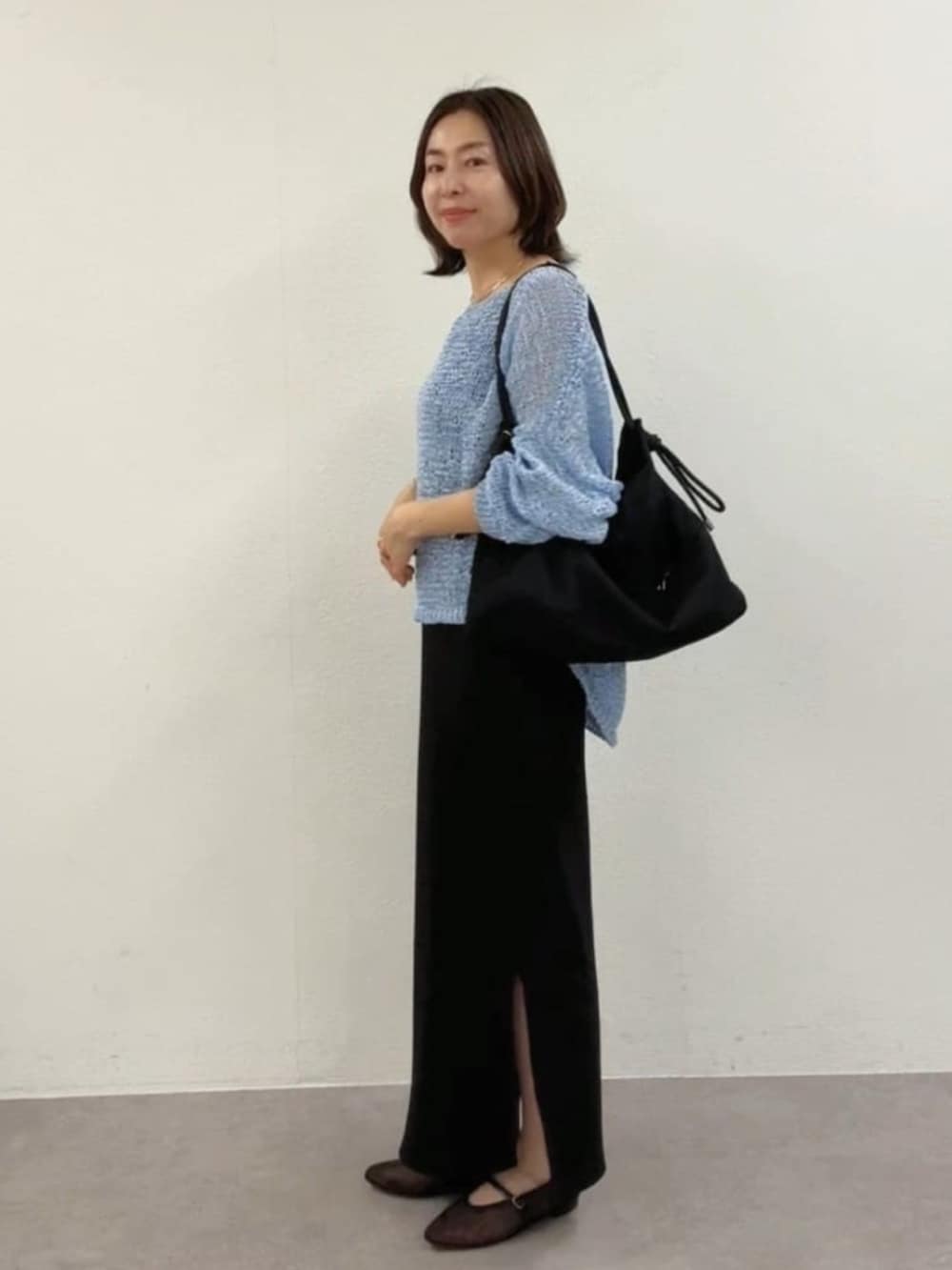 ブラック系のその他シューズ、ブルー系のニット/セーター、ブラック系のワンピースを着用したレディースの春コーディネートの2枚目の写真