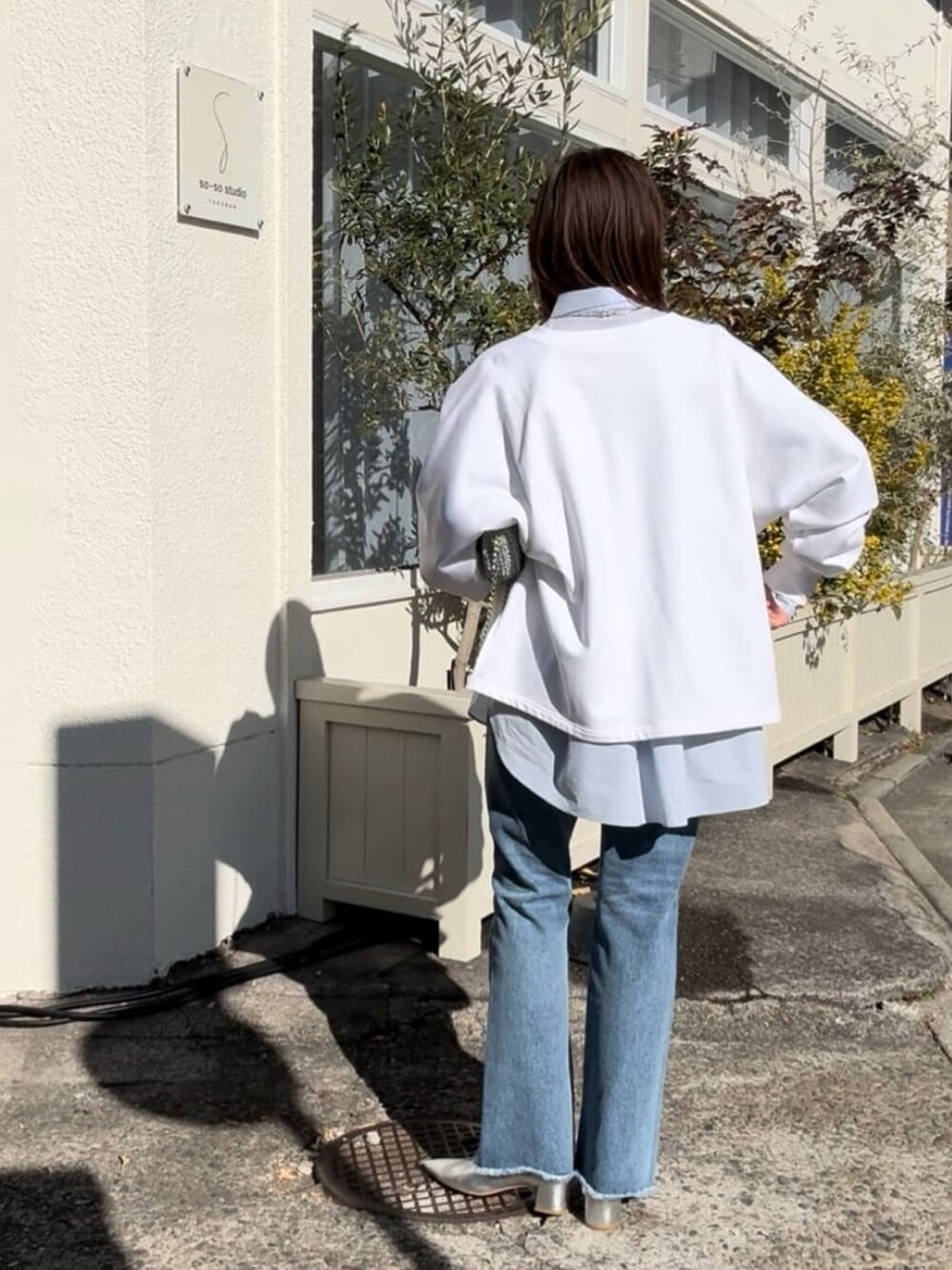 ホワイト系のスウェット、ブルー系のシャツ/ブラウス、ブルー系のデニムパンツを着用したレディースの冬コーディネートの3枚目の写真