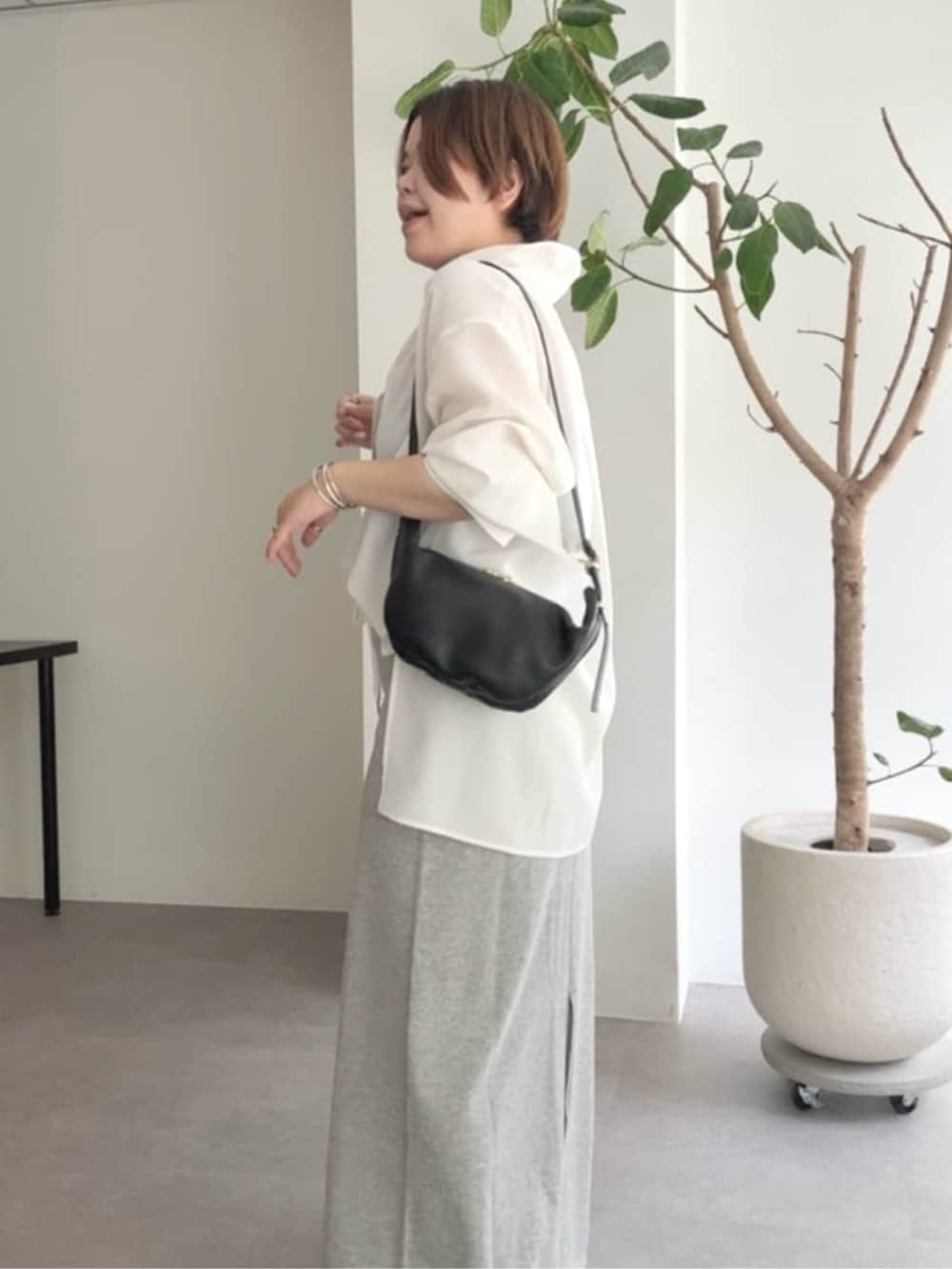 ブラック系のショルダーバッグ、グレー系のスカート、ホワイト系のシャツ/ブラウスを着用したレディースの春コーディネートの5枚目の写真