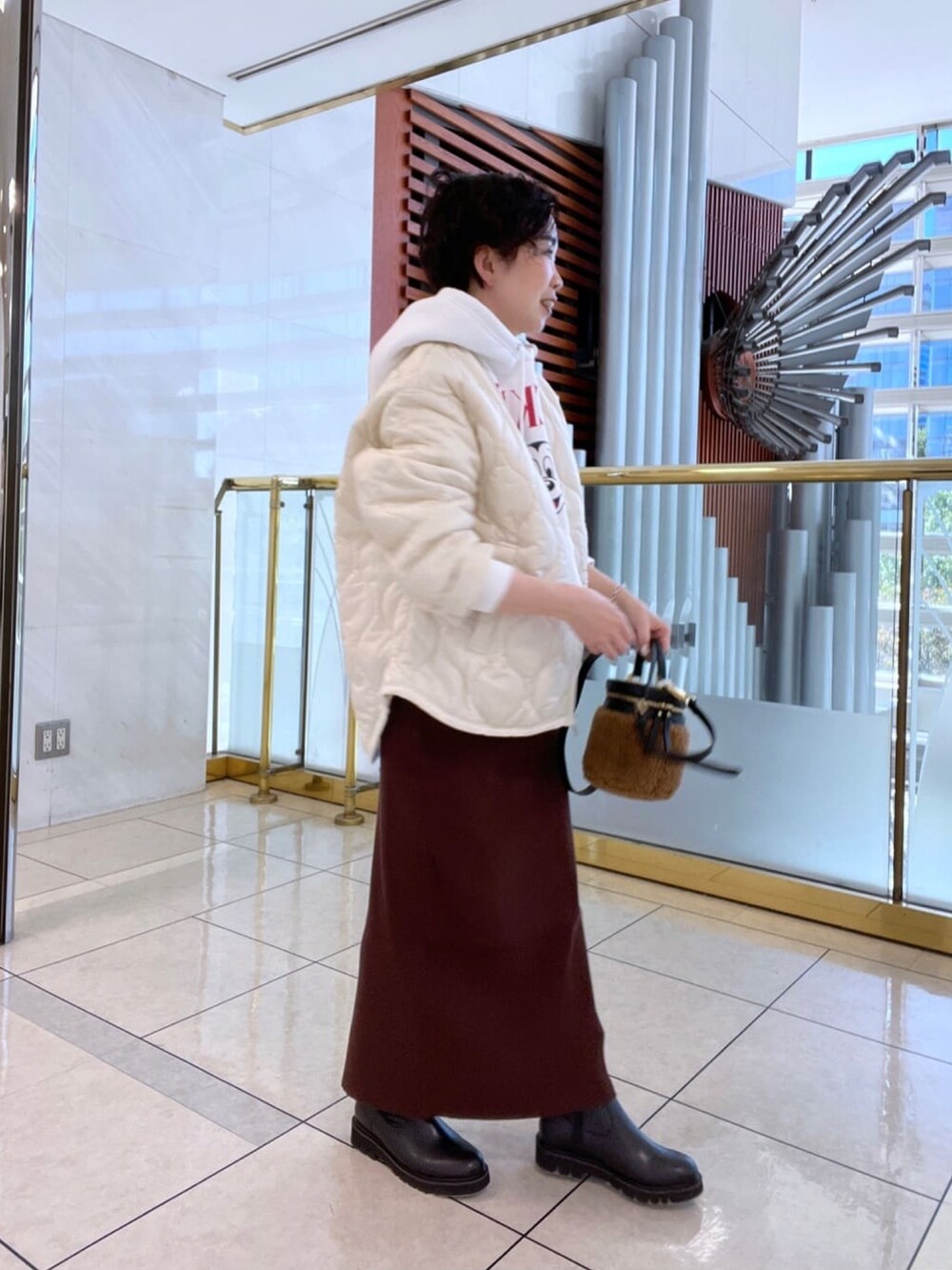 ブラウン系のスカート、ホワイト系のスウェット、ホワイト系のダウンジャケット/コートを着用したレディースの冬コーディネートの2枚目の写真