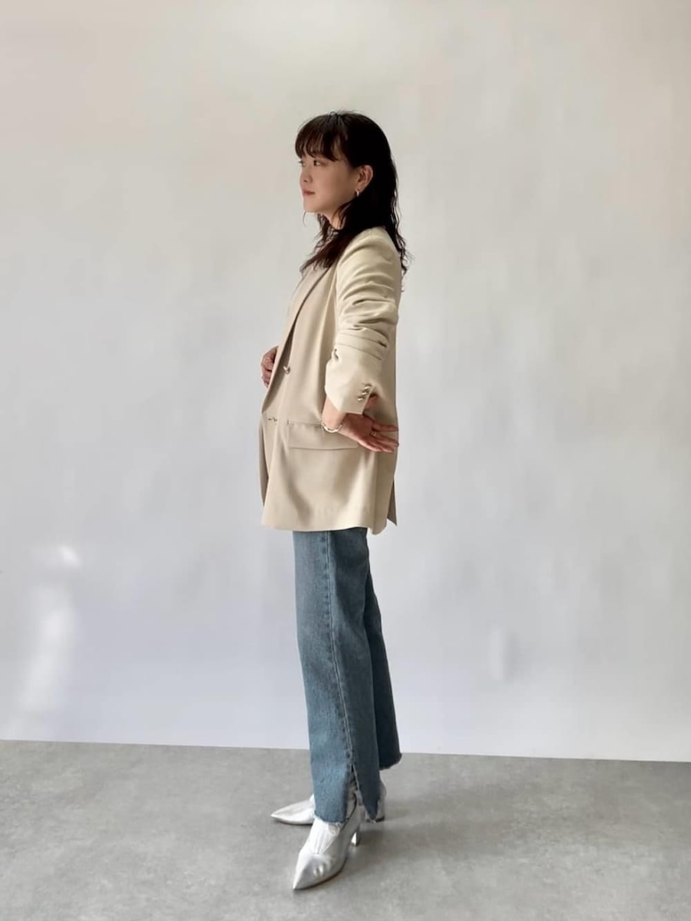 ベージュ系のテーラードジャケット、ホワイト系のニット/セーター、ブルー系のデニムパンツを着用したレディースの冬コーディネートの2枚目の写真