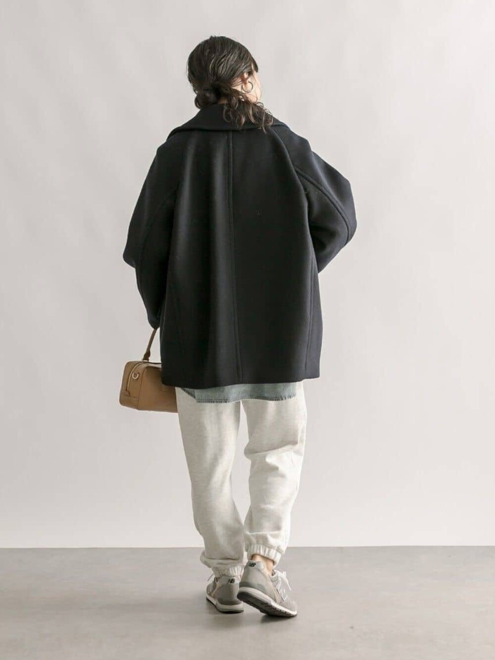 グレー系のスウェットパンツ、イエロー系のボストンバッグ、ブルー系のピーコートを着用したレディースの冬コーディネートの3枚目の写真