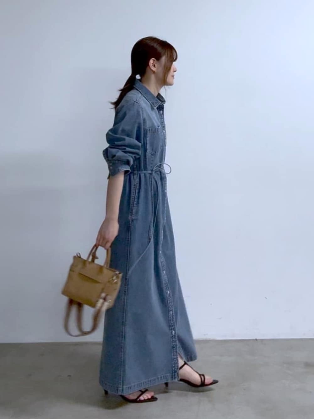 ベージュ系のトートバッグ、ブラック系のサンダル、ブルー系のワンピースを着用したレディースの春コーディネートの2枚目の写真