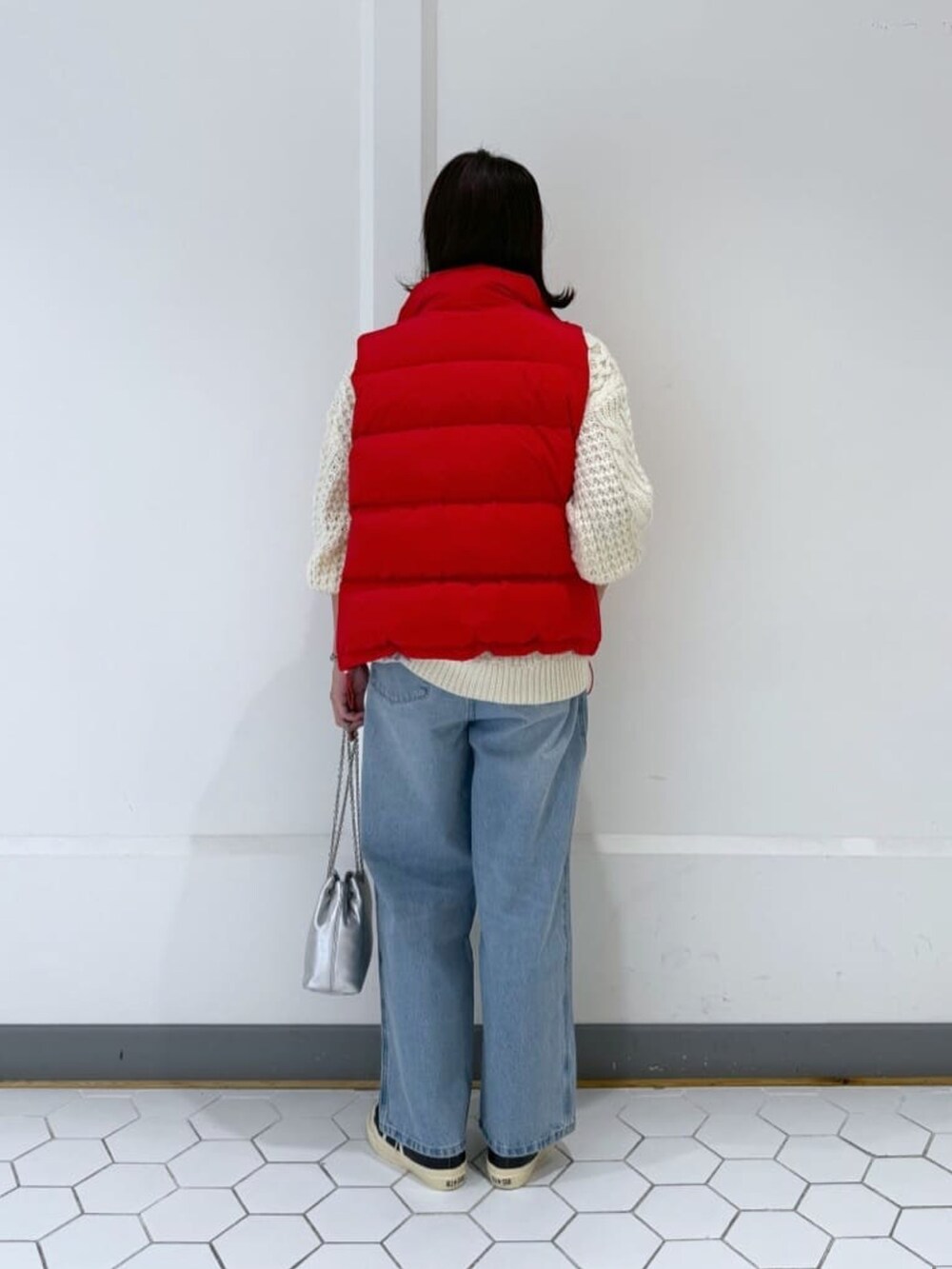レッド系のダウンベスト、ブルー系のデニムパンツ、ホワイト系のニット/セーターを着用したレディースの冬コーディネートの4枚目の写真