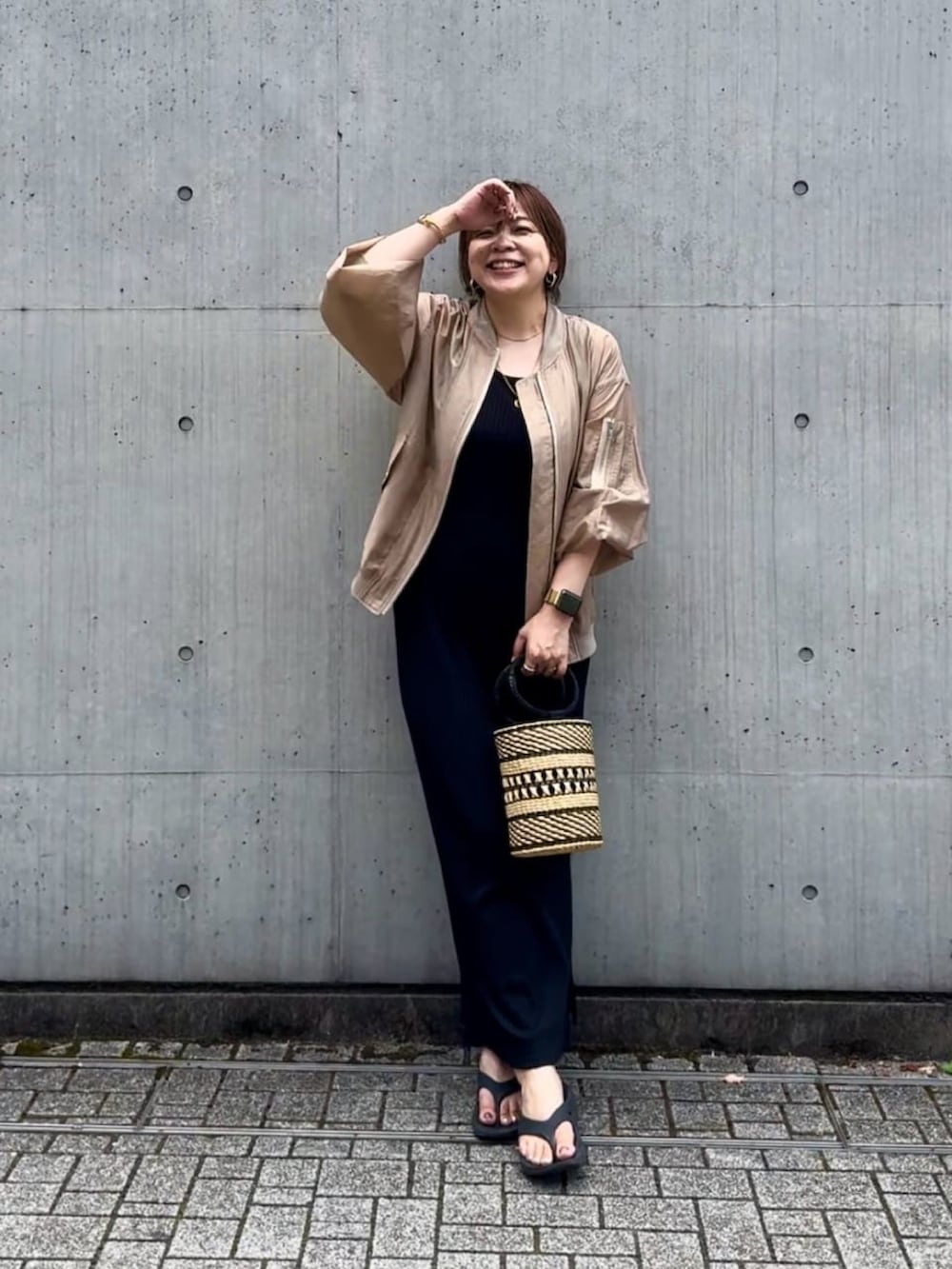 ベージュ系のブルゾン、ブラック系のワンピースを着用したレディースの夏コーディネートの2枚目の写真