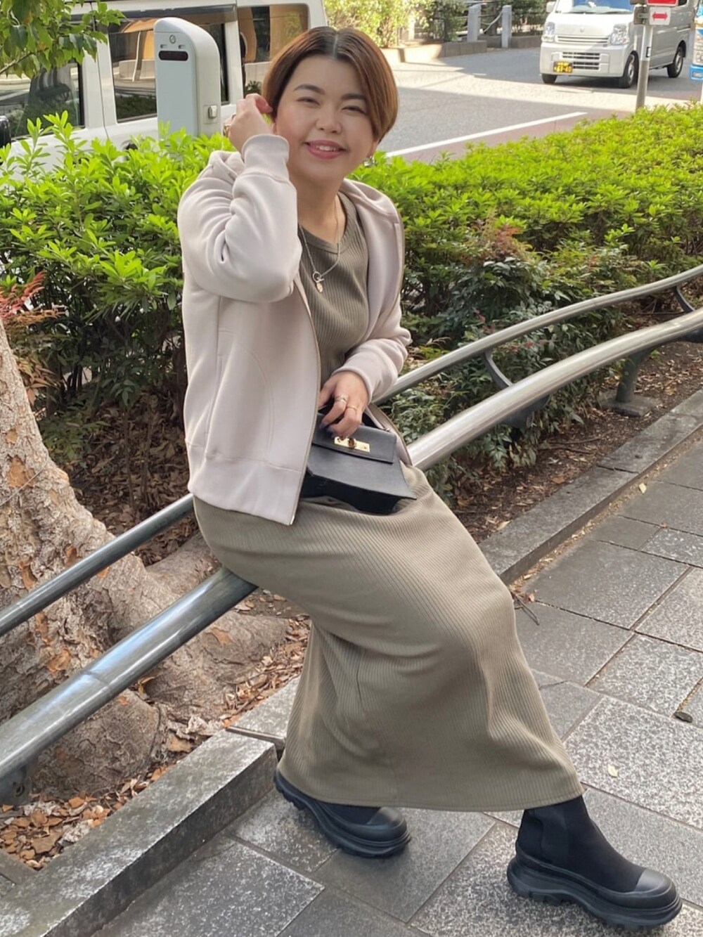 ベージュ系のパーカー、グリーン系のワンピース、ブラック系のハンドバッグを着用したレディースの秋コーディネートの2枚目の写真