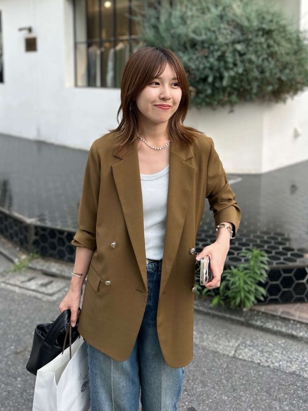 シルバー系のタンクトップ、ブラウン系のテーラードジャケット、ブルー系のデニムパンツを着用したレディースの夏コーディネートの4枚目の写真