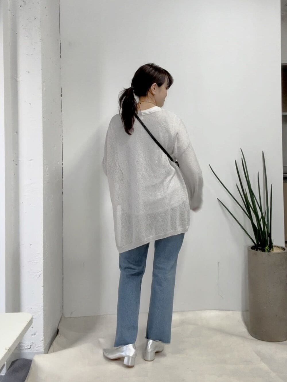 グレー系のニット/セーター、ブルー系のデニムパンツ、シルバー系のパンプスを着用したレディースの春コーディネートの3枚目の写真