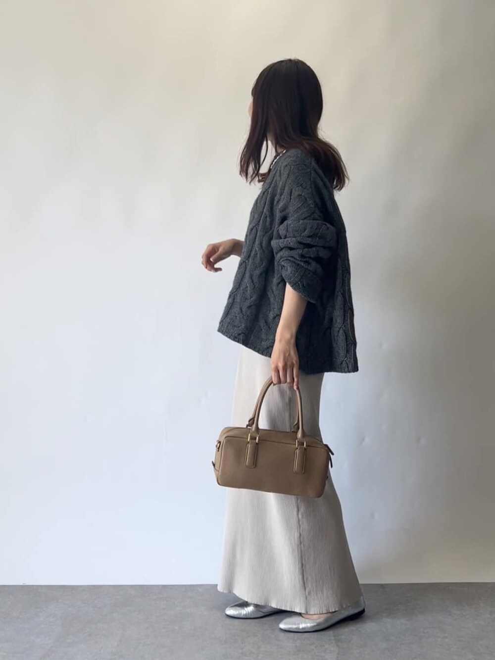 ベージュ系のスカート、グレー系のニット/セーター、イエロー系のボストンバッグを着用したレディースの秋コーディネートの3枚目の写真