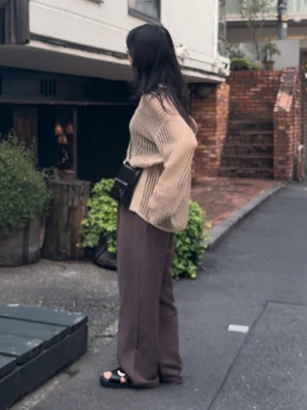 ホワイト系のニット/セーター、ブラウン系のスラックス、ブラック系のサンダルを着用したレディースの春コーディネートの2枚目の写真