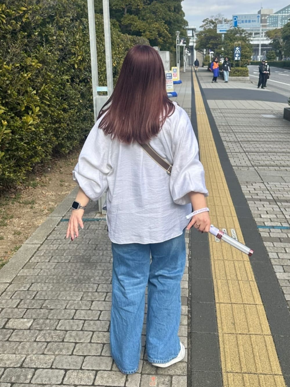 ブルー系のデニムパンツ、ブルー系のトートバッグ、ブラウン系のキャミソールを着用したレディースの春コーディネートの4枚目の写真