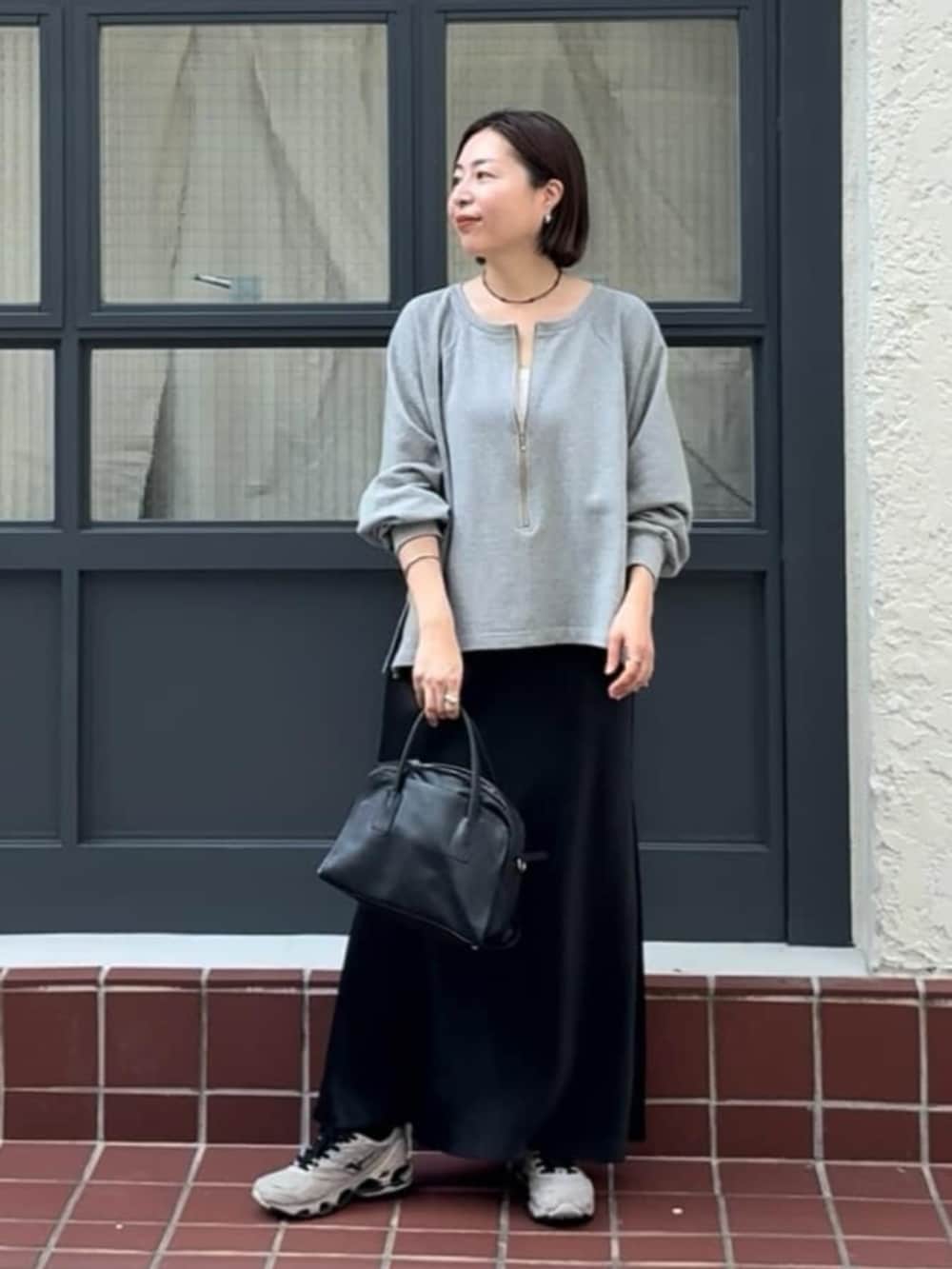 ブラック系のボストンバッグ、ブラック系のスカート、グレー系のテーラードジャケットを着用したレディースの冬コーディネートの2枚目の写真