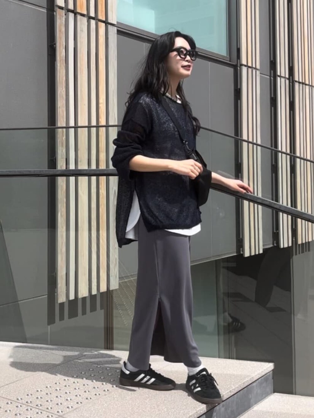 ブルー系のニット/セーター、ホワイト系のシャツ/ブラウス、ブラック系のスカートを着用したレディースの春コーディネートの2枚目の写真