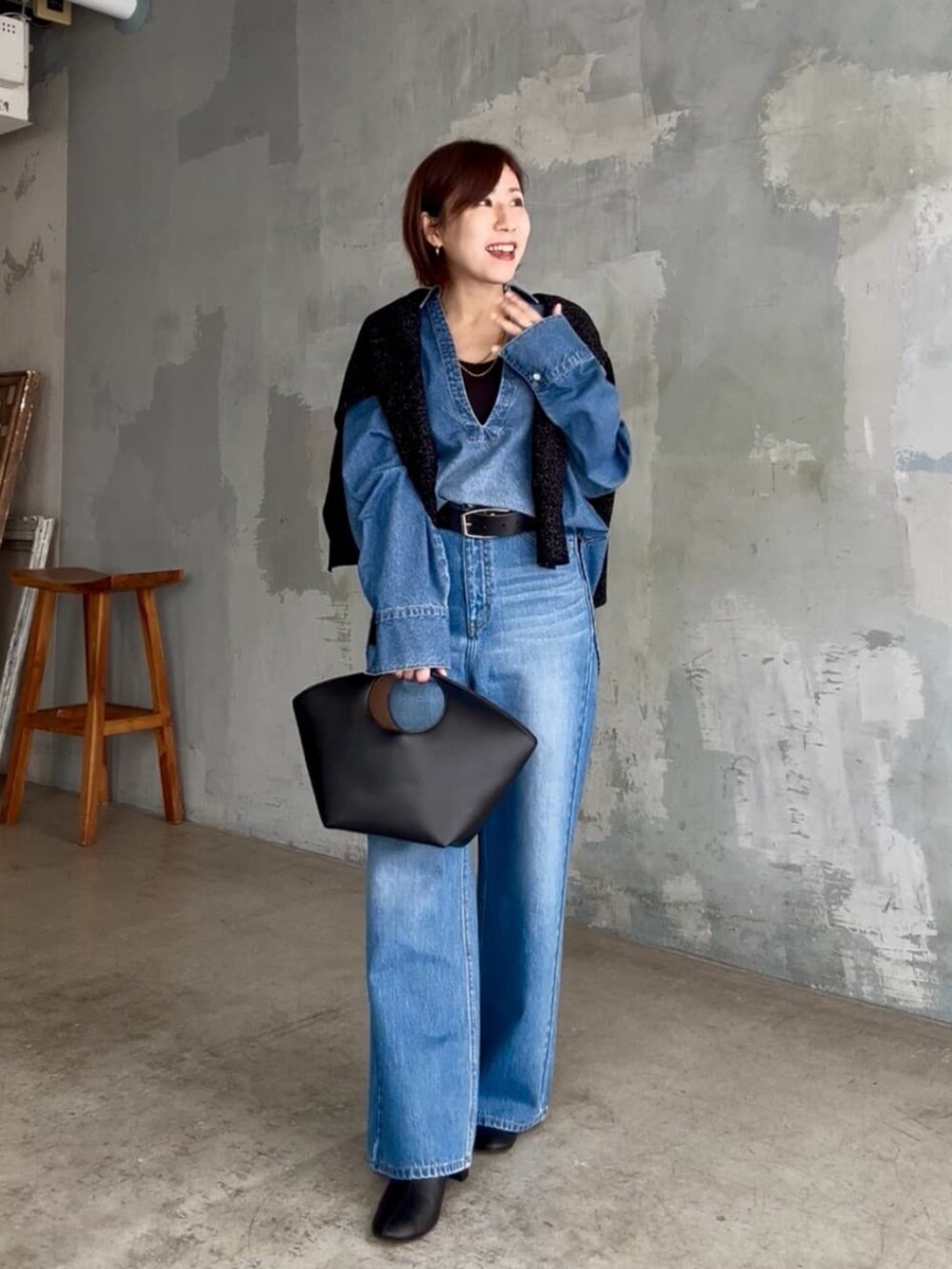 ブラック系のニット/セーター、ブルー系のシャツ/ブラウス、ブルー系のデニムパンツを着用したレディースの秋コーディネートの2枚目の写真