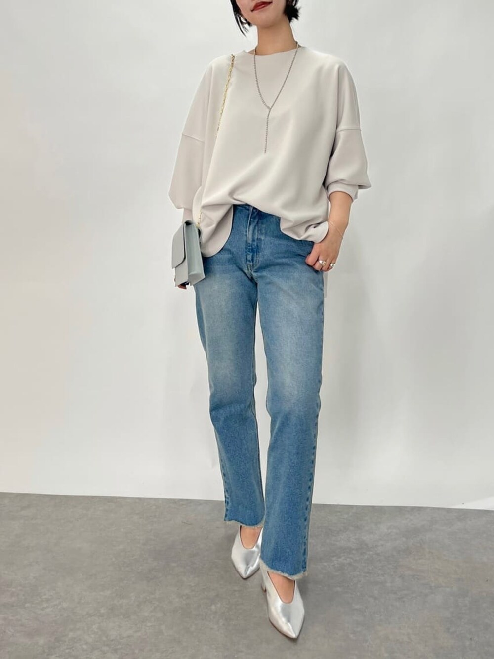 グレー系のTシャツ/カットソー、ブルー系のショルダーバッグ、ブルー系のデニムパンツを着用したレディースの冬コーディネートの2枚目の写真