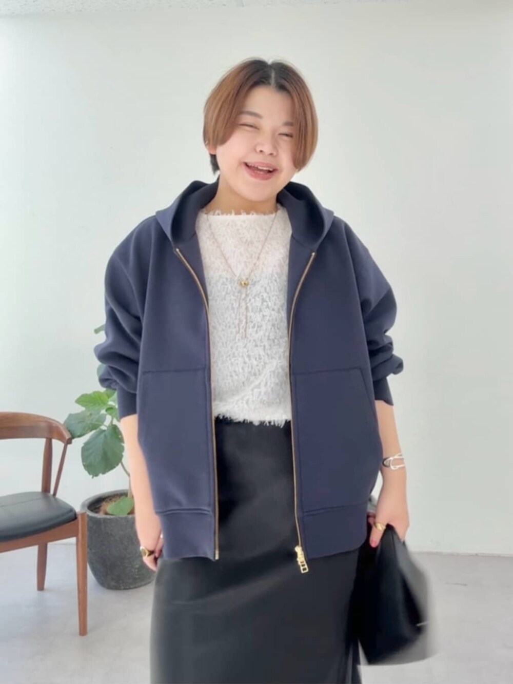 ブラック系のハンドバッグ、ブラック系のスカート、ブラック系のブーツを着用したレディースの冬コーディネートの3枚目の写真