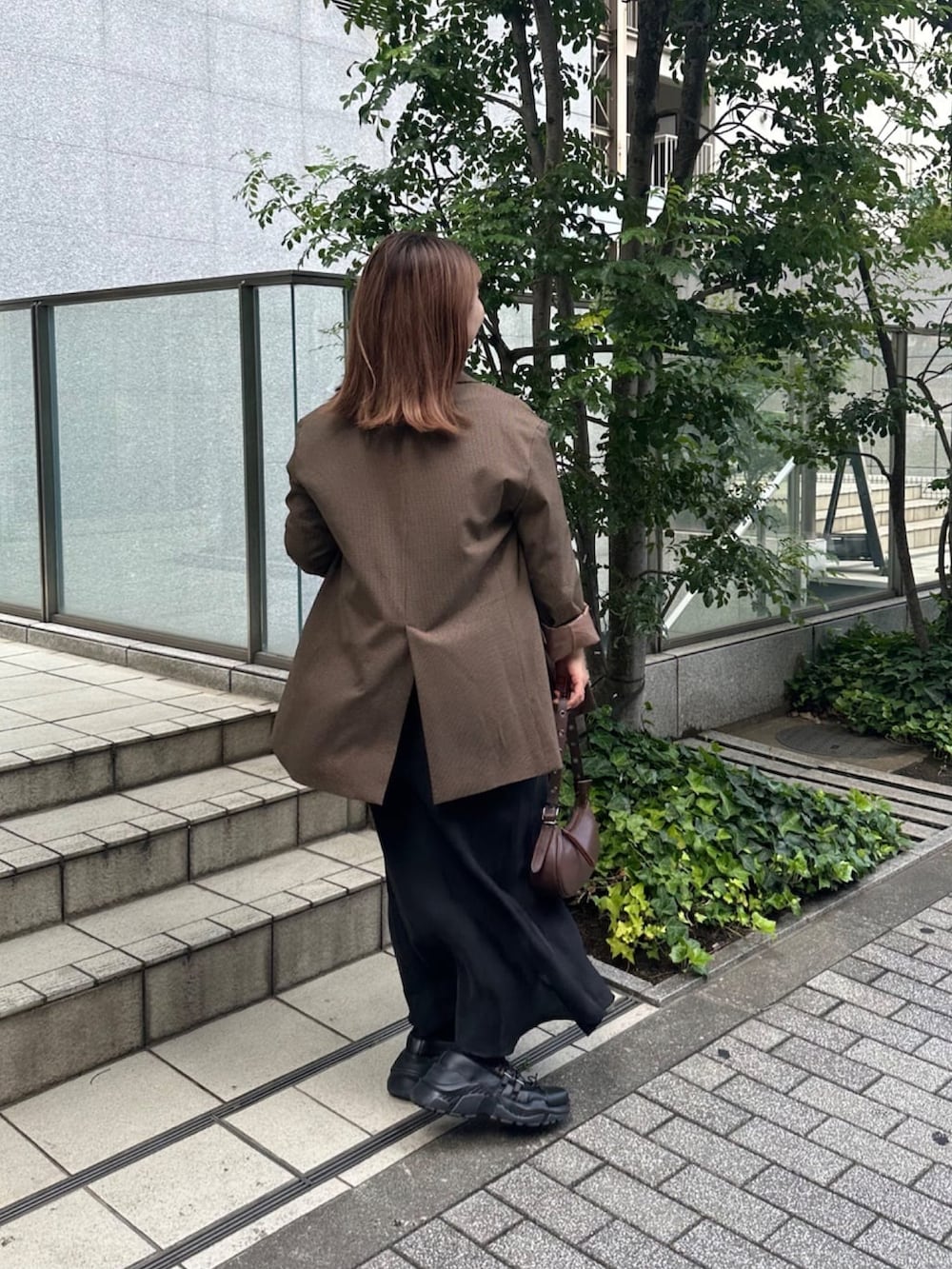 ブラウン系のテーラードジャケット、ホワイト系のTシャツ/カットソー、ブラック系のスカートを着用したレディースの秋コーディネートの3枚目の写真