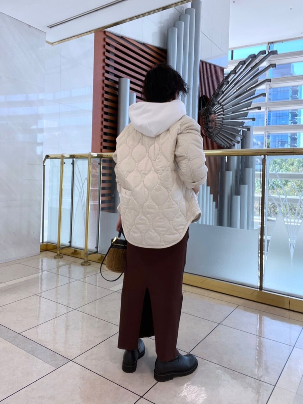 ブラウン系のスカート、ホワイト系のスウェット、ホワイト系のダウンジャケット/コートを着用したレディースの冬コーディネートの3枚目の写真