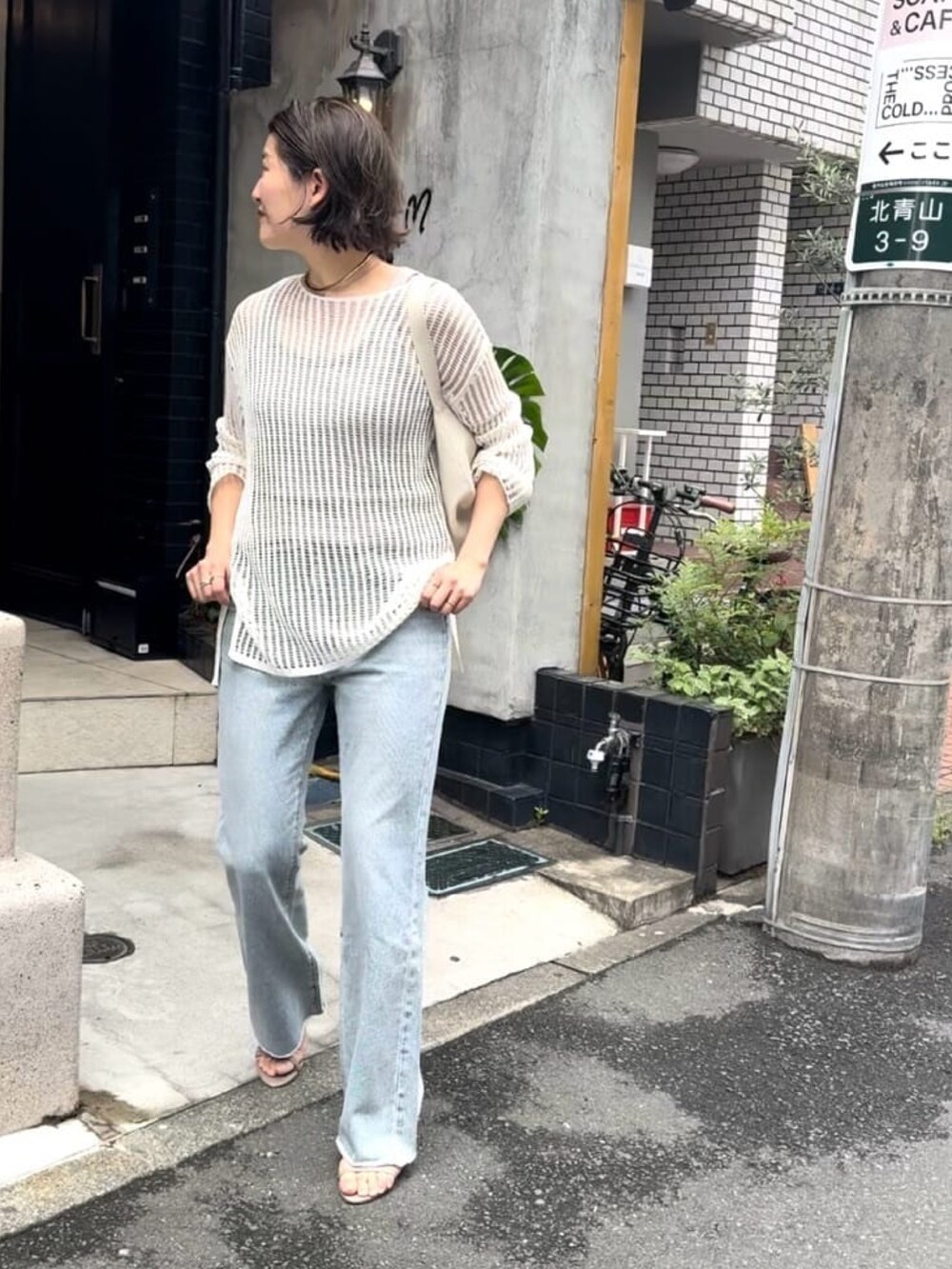 ホワイト系のニット/セーター、ブルー系のデニムパンツ、ホワイト系のボディバッグ/ウエストポーチを着用したレディースの春コーディネートの5枚目の写真