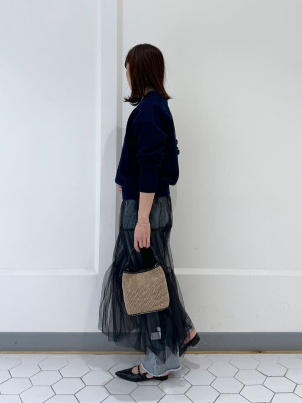 ブルー系のニット/セーター、ブラック系のスカート、ブラック系のハンドバッグを着用したレディースの春コーディネートの3枚目の写真