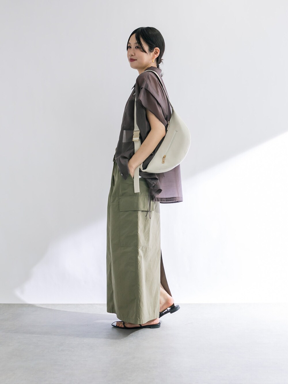 グリーン系のスカート、ホワイト系のキャミソール、ブラック系のサンダルを着用したレディースの春コーディネートの2枚目の写真