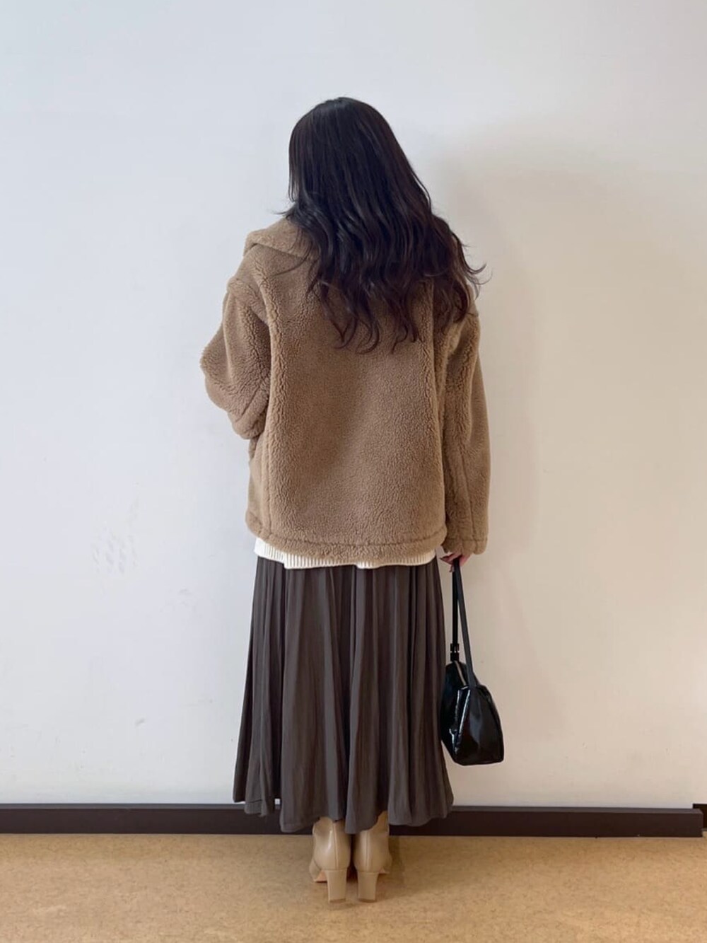 ホワイト系のニット/セーター、ベージュ系のその他アウター、グリーン系のスカートを着用したレディースの秋コーディネートの3枚目の写真