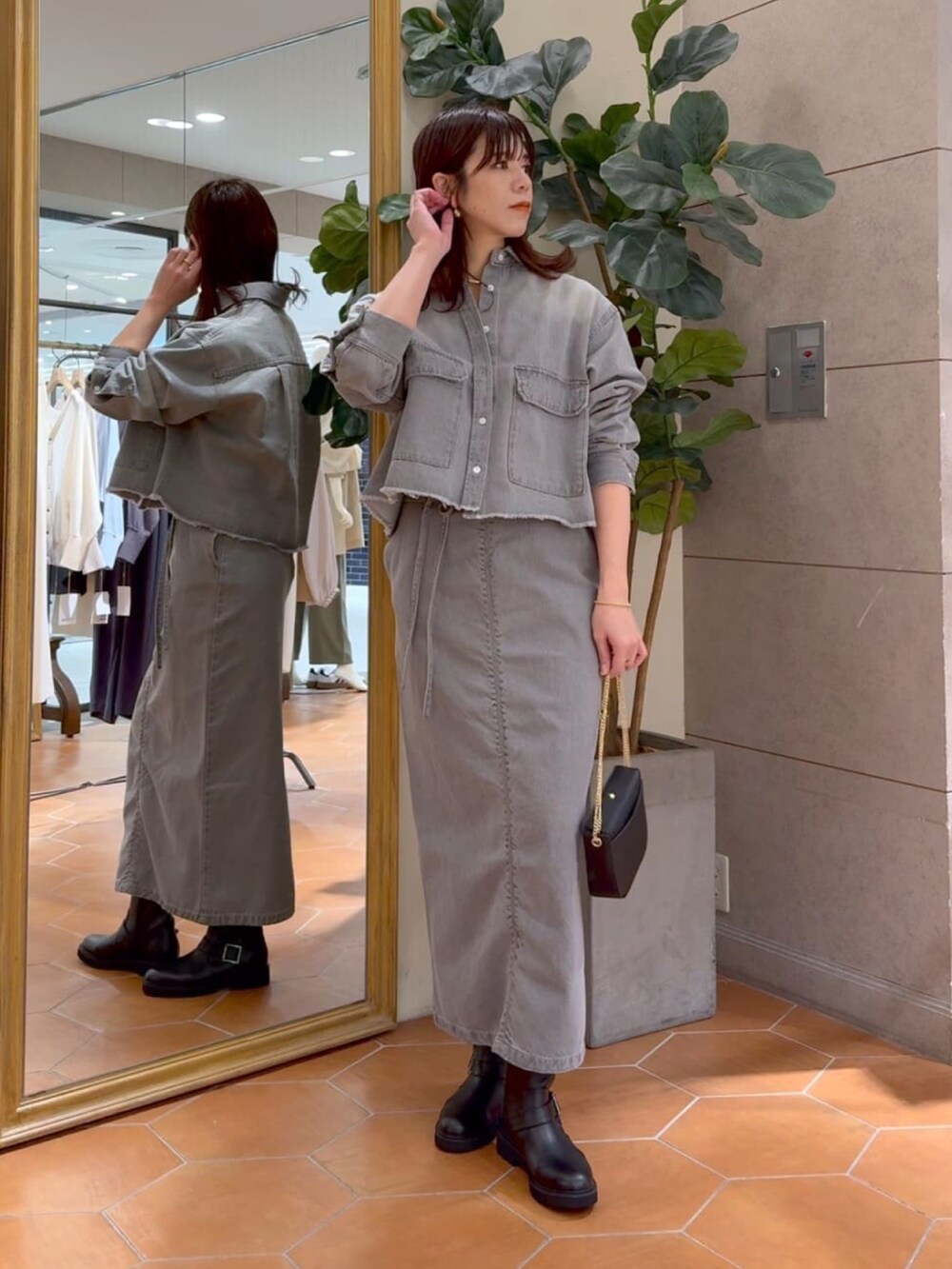 グレー系のシャツ/ブラウス、グレー系のデニムスカート、ブラック系のマウンテンパーカーを着用したレディースの冬コーディネートの5枚目の写真