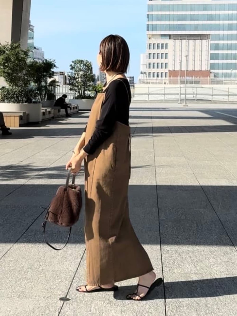 ブラウン系のワンピース、ブラック系のサンダル、ブラウン系のハンドバッグを着用したレディースの夏コーディネートの2枚目の写真