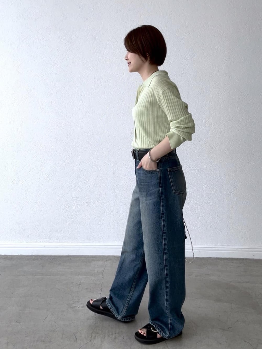 グリーン系のカーディガン/ボレロ、ブルー系のデニムパンツ、ブラック系のハンドバッグを着用したレディースの夏コーディネートの2枚目の写真