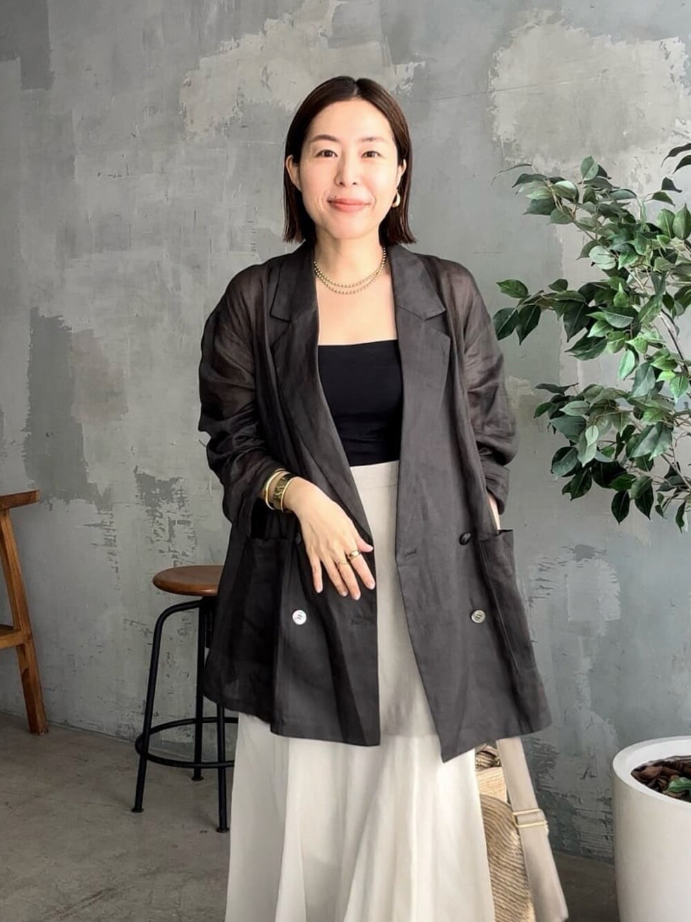 ブラック系のテーラードジャケット、ブラック系のキャミソール、ベージュ系のスカートを着用したレディースの夏コーディネートの4枚目の写真