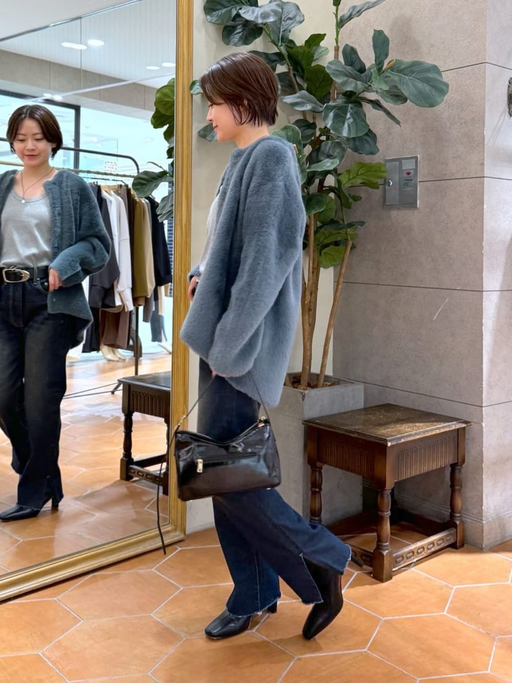 ブルー系のカーディガン/ボレロ、ブルー系のデニムパンツ、ブラック系のショルダーバッグを着用したレディースの秋コーディネートの2枚目の写真