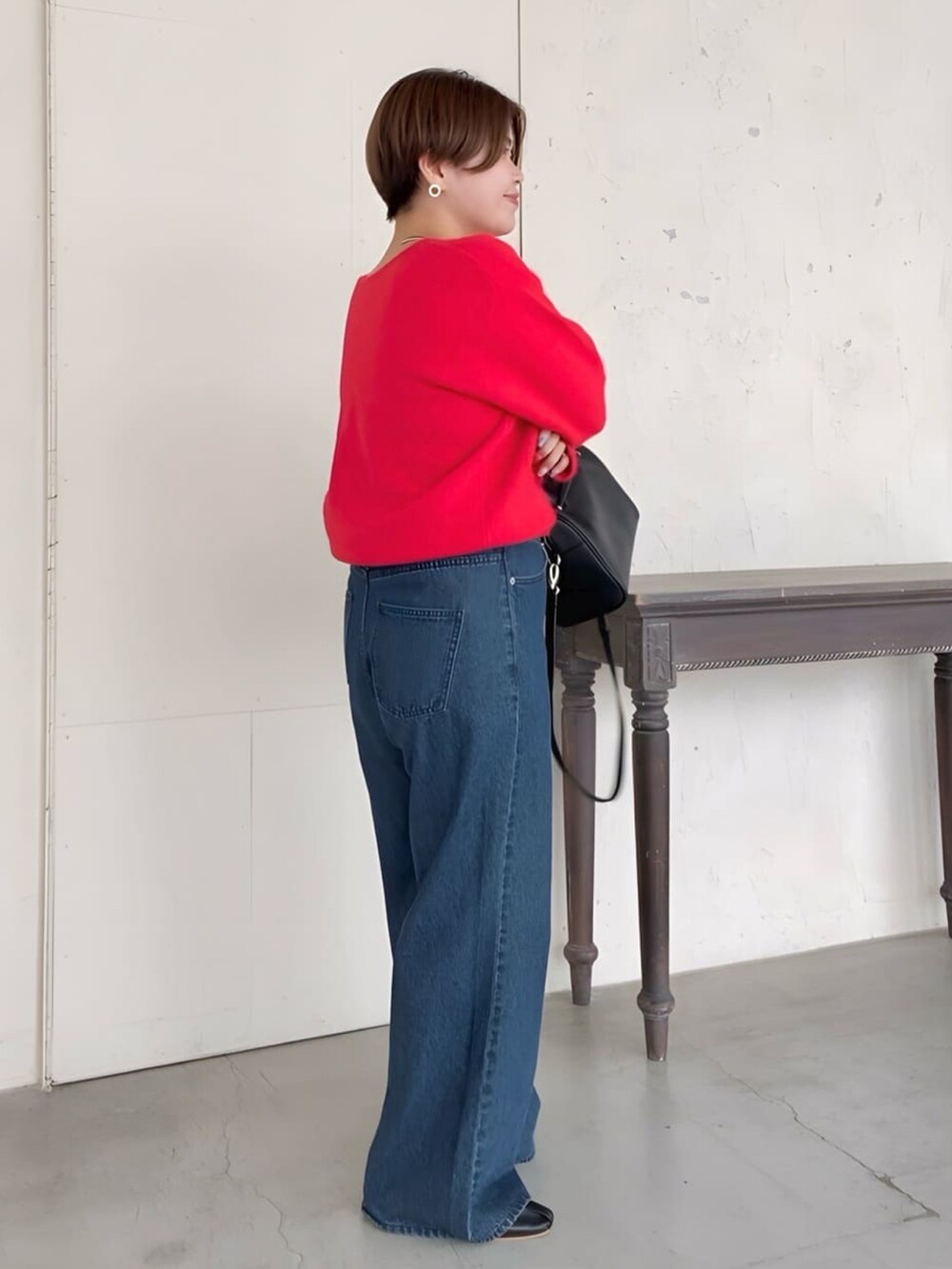 ブルー系のデニムパンツ、レッド系のニット/セーター、ブラック系のバッグを着用したレディースの夏コーディネートの2枚目の写真