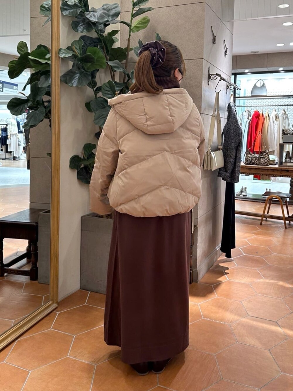 ブラウン系のワンピース、ブラック系のブーツ、ブラック系のダウンジャケット/コートを着用したレディースの冬コーディネートの3枚目の写真