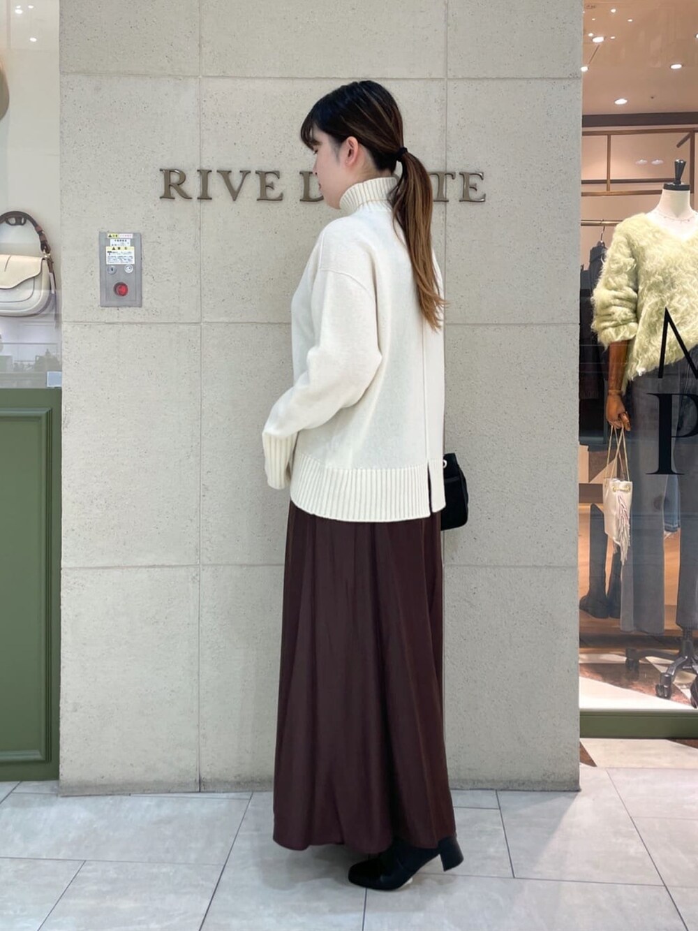 イエロー系のボストンバッグ、ホワイト系のニット/セーター、グレー系のその他アウターを着用したレディースの秋コーディネートの3枚目の写真