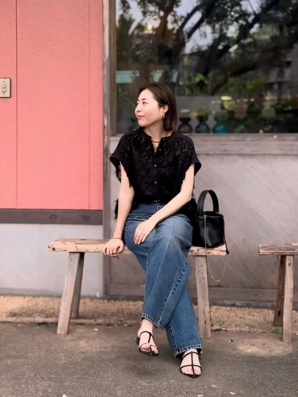 ブラック系のシャツ/ブラウス、ブラック系のサンダル、ブルー系のデニムパンツを着用したレディースの夏コーディネートの4枚目の写真