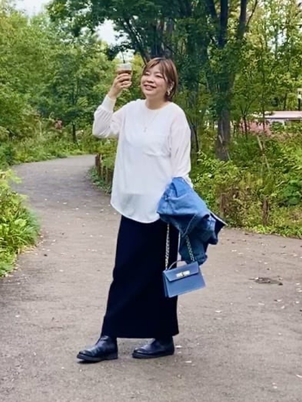 グレー系のシャツ/ブラウス、ブルー系のハンドバッグ、ブラック系のスカートを着用したレディースの春コーディネートの2枚目の写真