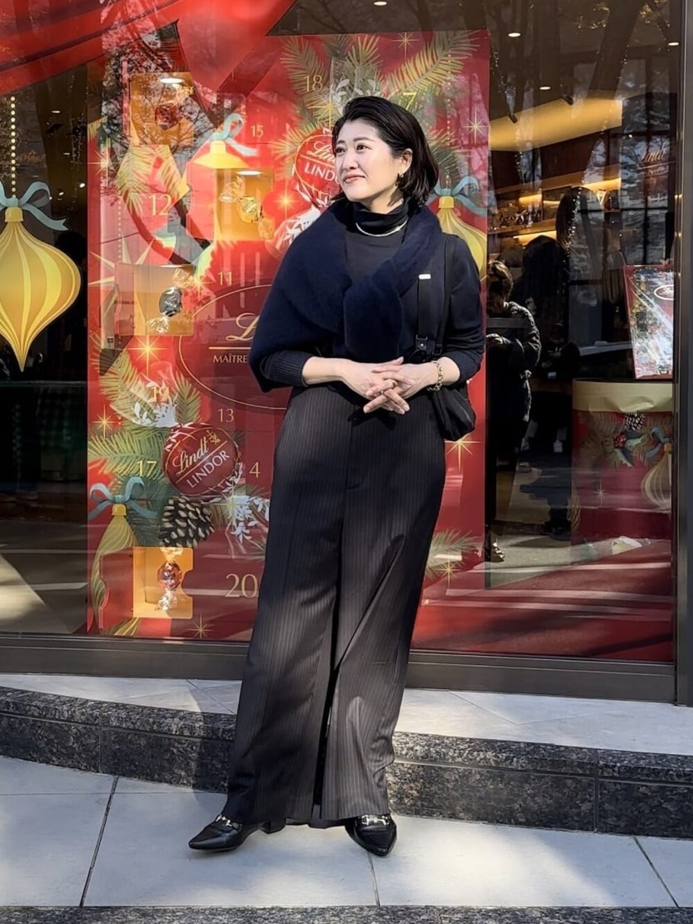 ブルー系のニット/セーター、ブラック系のスラックス、ブラック系のローファーを着用したレディースの冬コーディネートの2枚目の写真