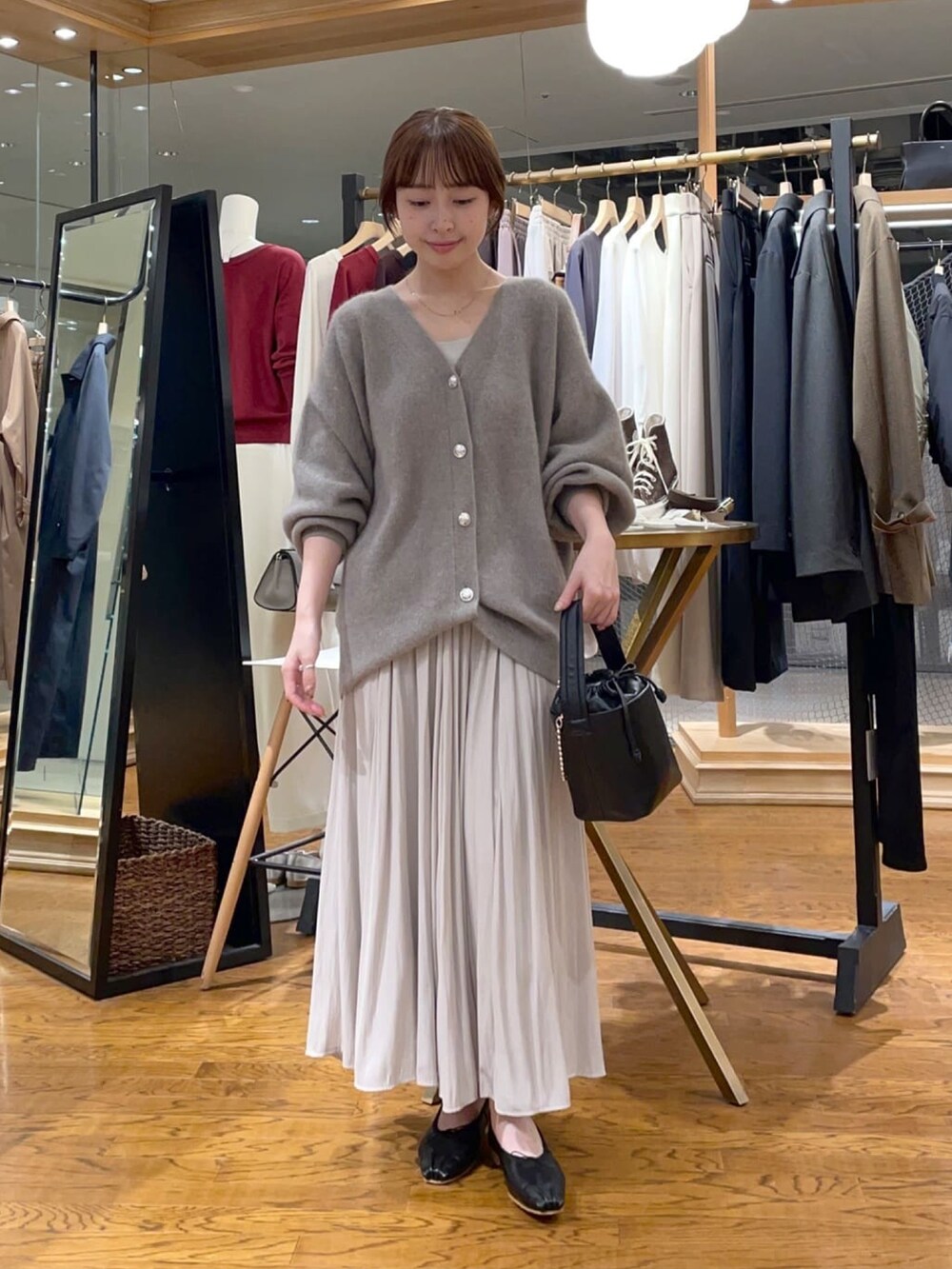 ブラウン系のカーディガン/ボレロ、ベージュ系のスカート、ブラック系のハンドバッグを着用したレディースの冬コーディネートの2枚目の写真