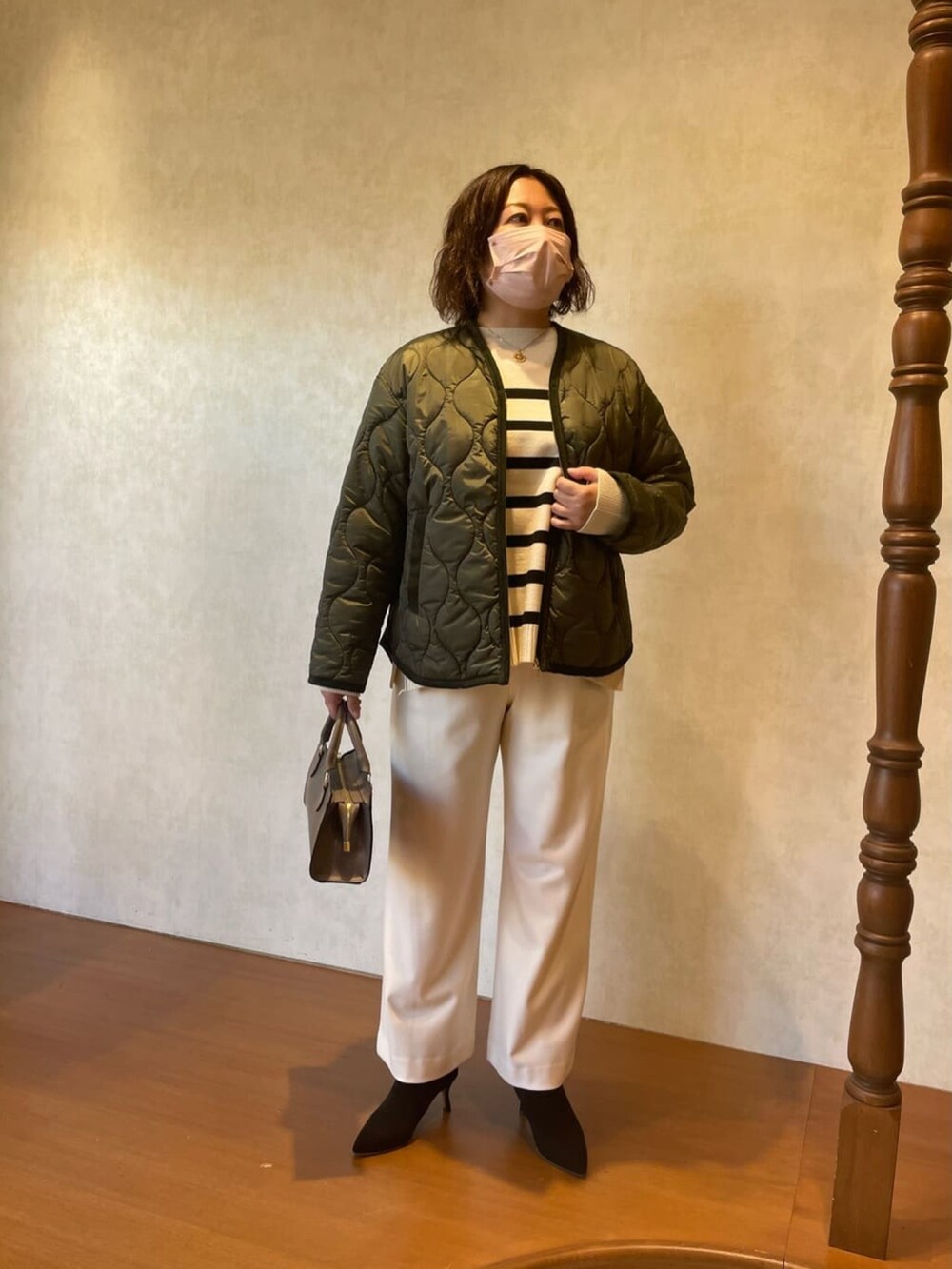 グリーン系のダウンジャケット/コート、ホワイト系のニット/セーター、ブラック系のブーツを着用したレディースの秋コーディネートの2枚目の写真