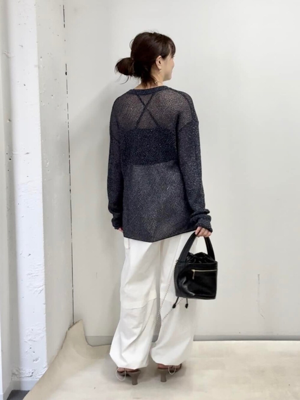 ブルー系のニット/セーター、ホワイト系のカーゴパンツ、ブラック系のハンドバッグを着用したレディースの夏コーディネートの3枚目の写真