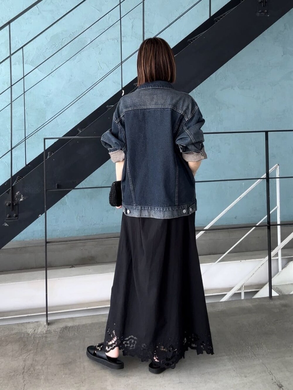 ブルー系のデニムジャケット、ブラック系のワンピース、ブラック系のサンダルを着用したレディースの夏コーディネートの3枚目の写真