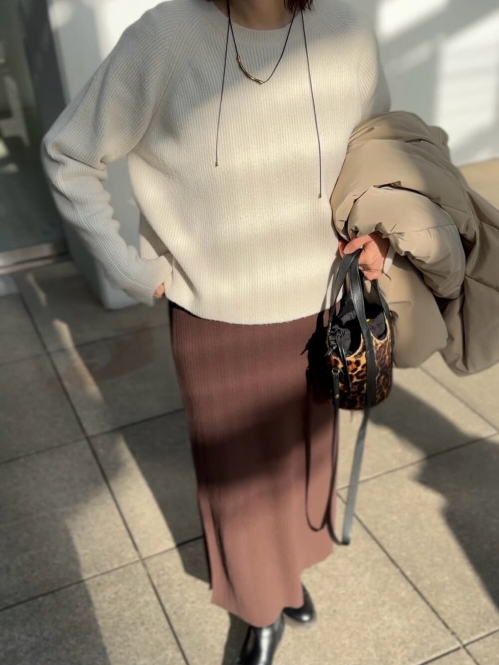 ホワイト系のニット/セーター、ブラウン系のワンピースを着用したレディースの冬コーディネートの3枚目の写真