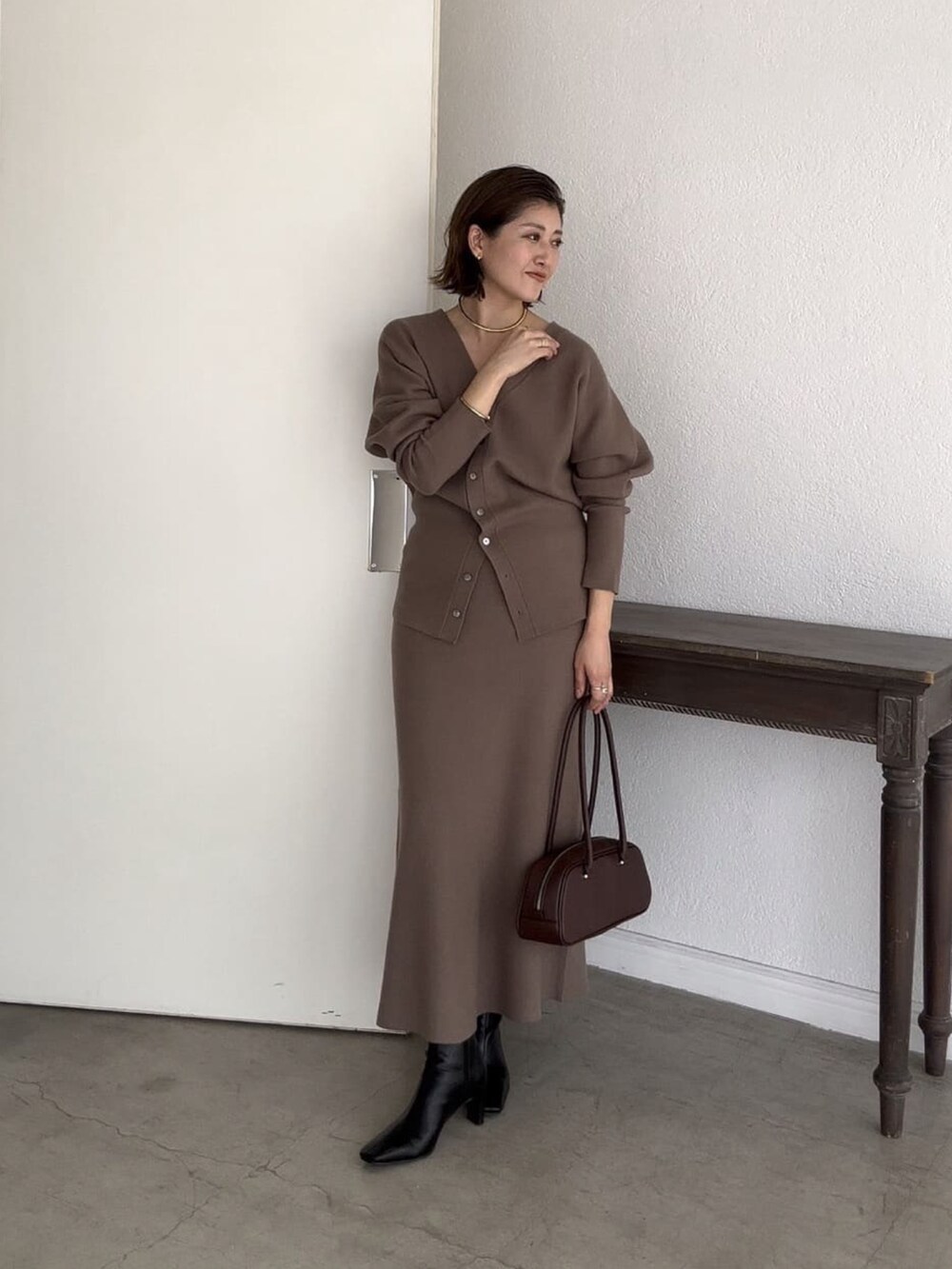 ブラウン系のカーディガン/ボレロ、ブラウン系のスカート、ブラック系のショルダーバッグを着用したレディースの秋コーディネートの2枚目の写真