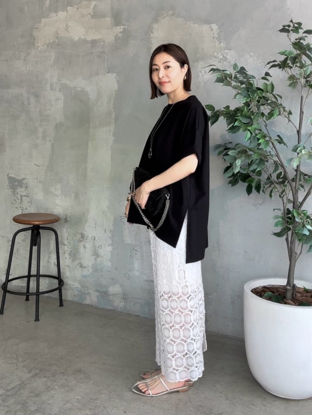 ブラック系のTシャツ/カットソー、ブラック系のショルダーバッグ、ホワイト系のスカートを着用したレディースの夏コーディネートの2枚目の写真