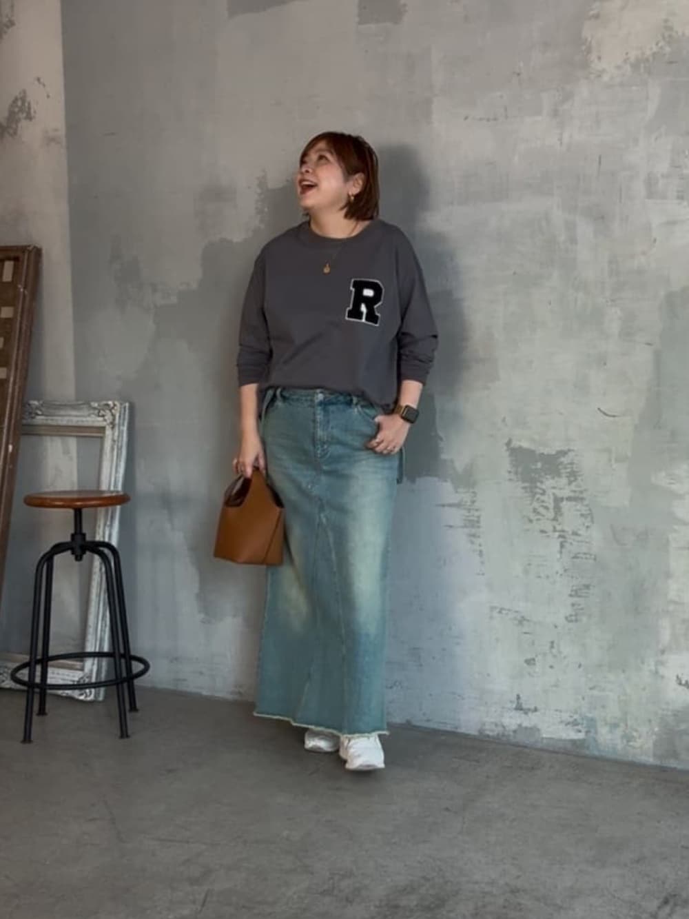 グレー系のTシャツ/カットソー、ブルー系のデニムスカート、イエロー系のハンドバッグを着用したレディースの冬コーディネートの2枚目の写真