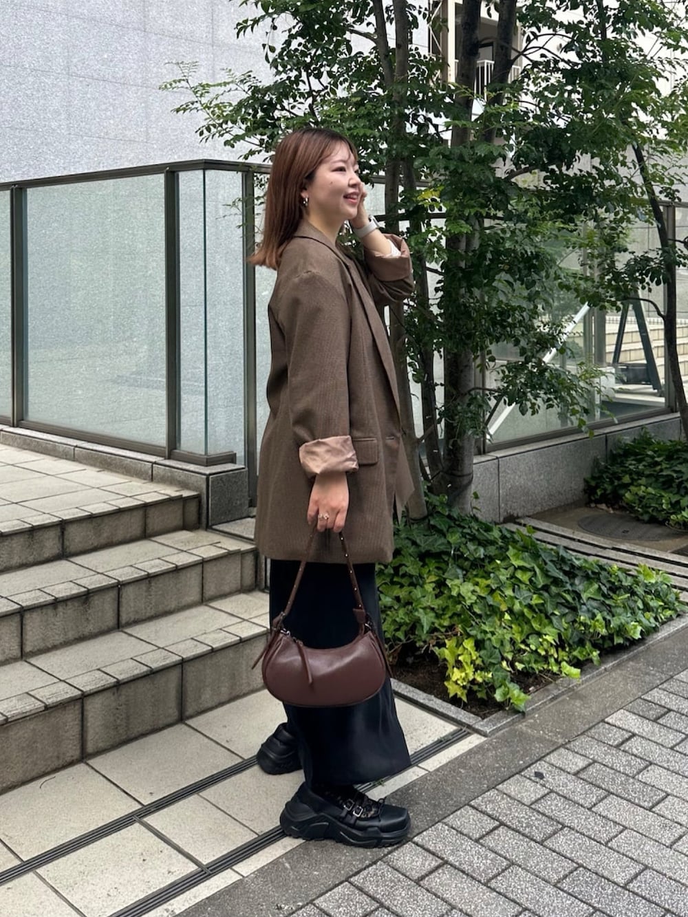 ブラウン系のテーラードジャケット、ホワイト系のTシャツ/カットソー、ブラック系のスカートを着用したレディースの秋コーディネートの2枚目の写真