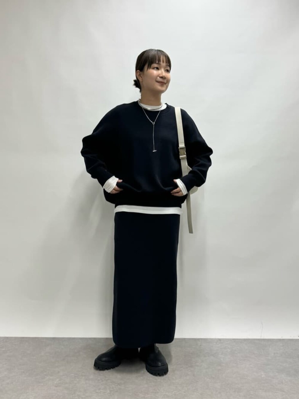 ホワイト系のボディバッグ/ウエストポーチ、ブルー系のニット/セーター、ホワイト系のTシャツ/カットソーを着用したレディースの冬コーディネートの3枚目の写真